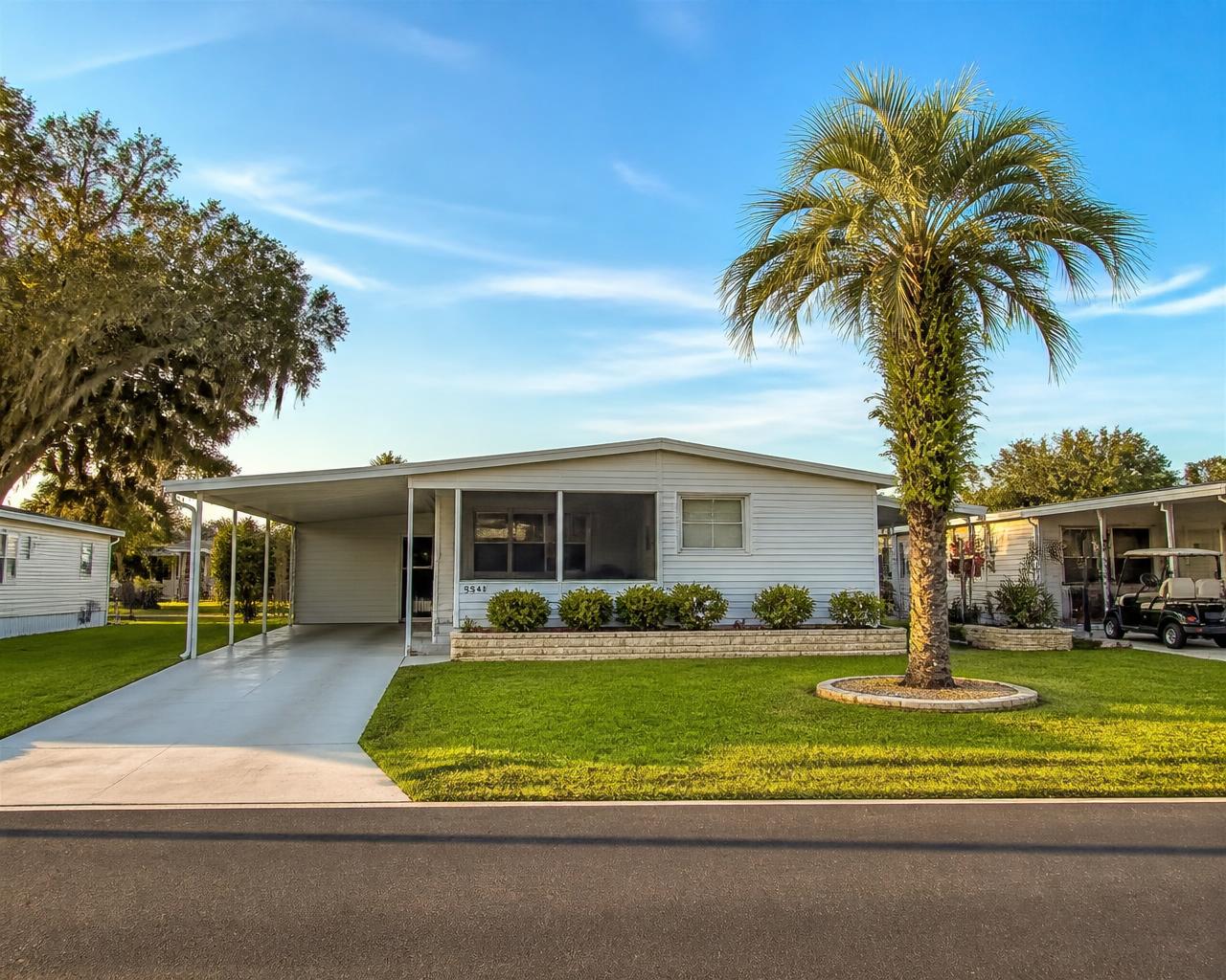 Manufactured home with a mown lawn and palm tree on an Ocala, Florida street